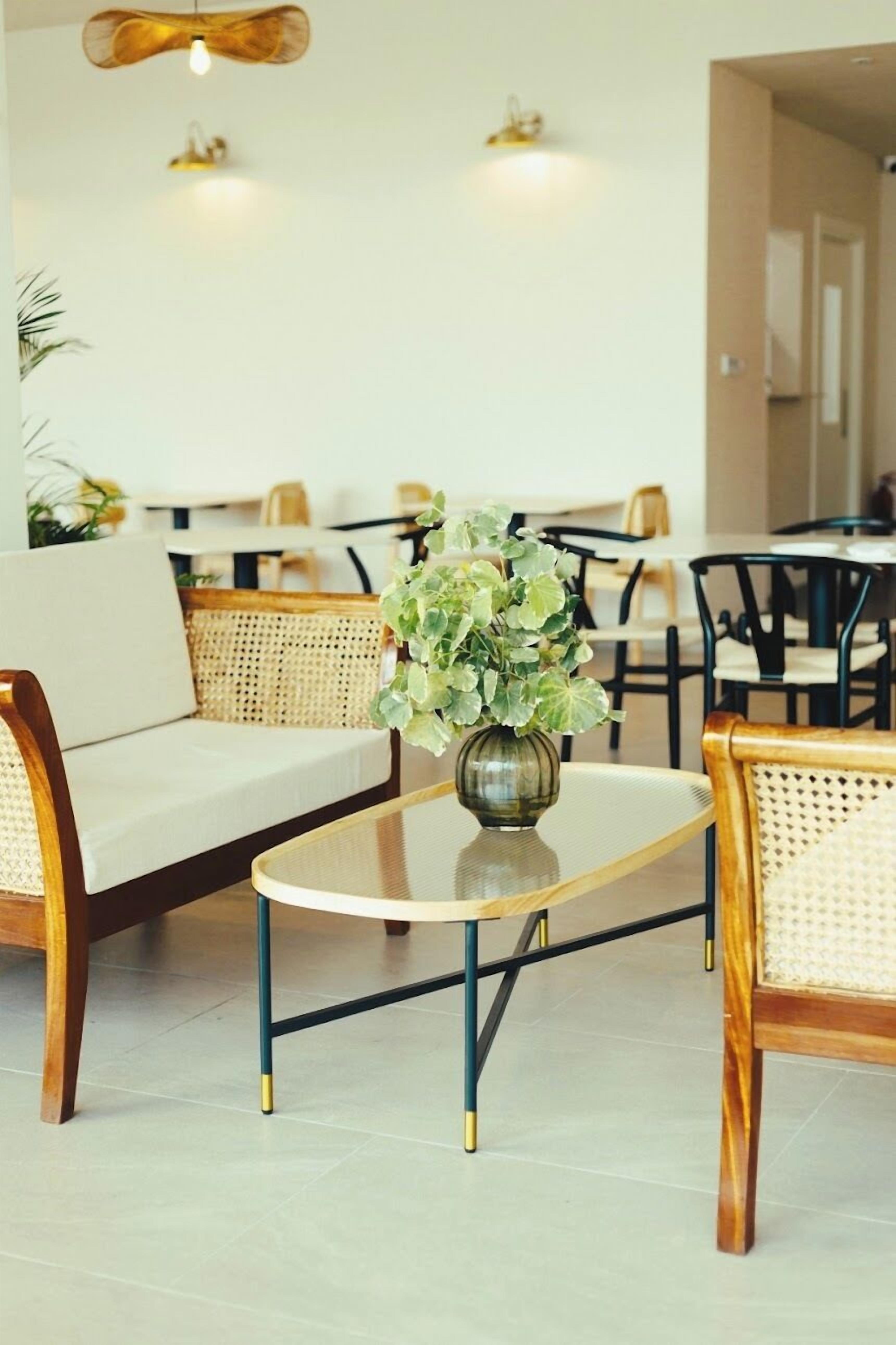 A modern lounge area with a sofa, a coffee table, and a vase of flowers.