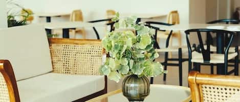 A modern lounge area with a sofa, a coffee table, and a vase of flowers.