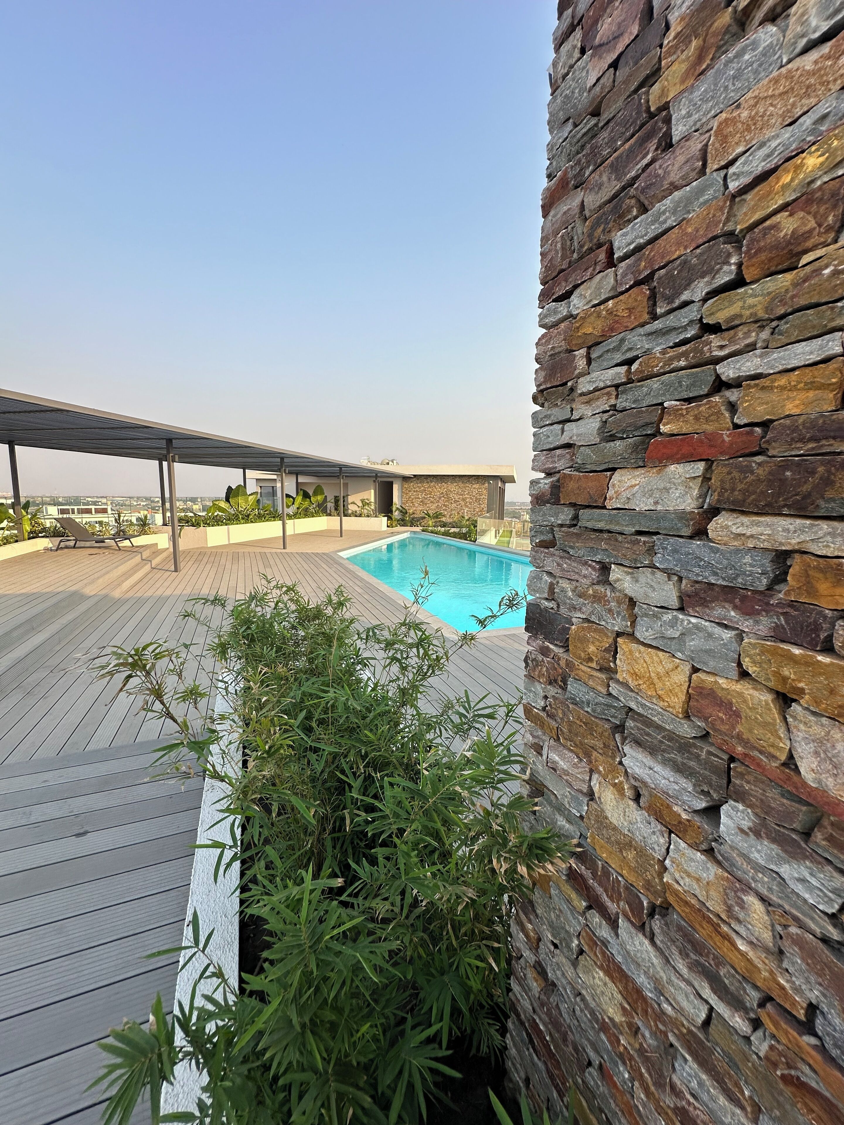 A rooftop pool area with a stone wall and wooden deck.