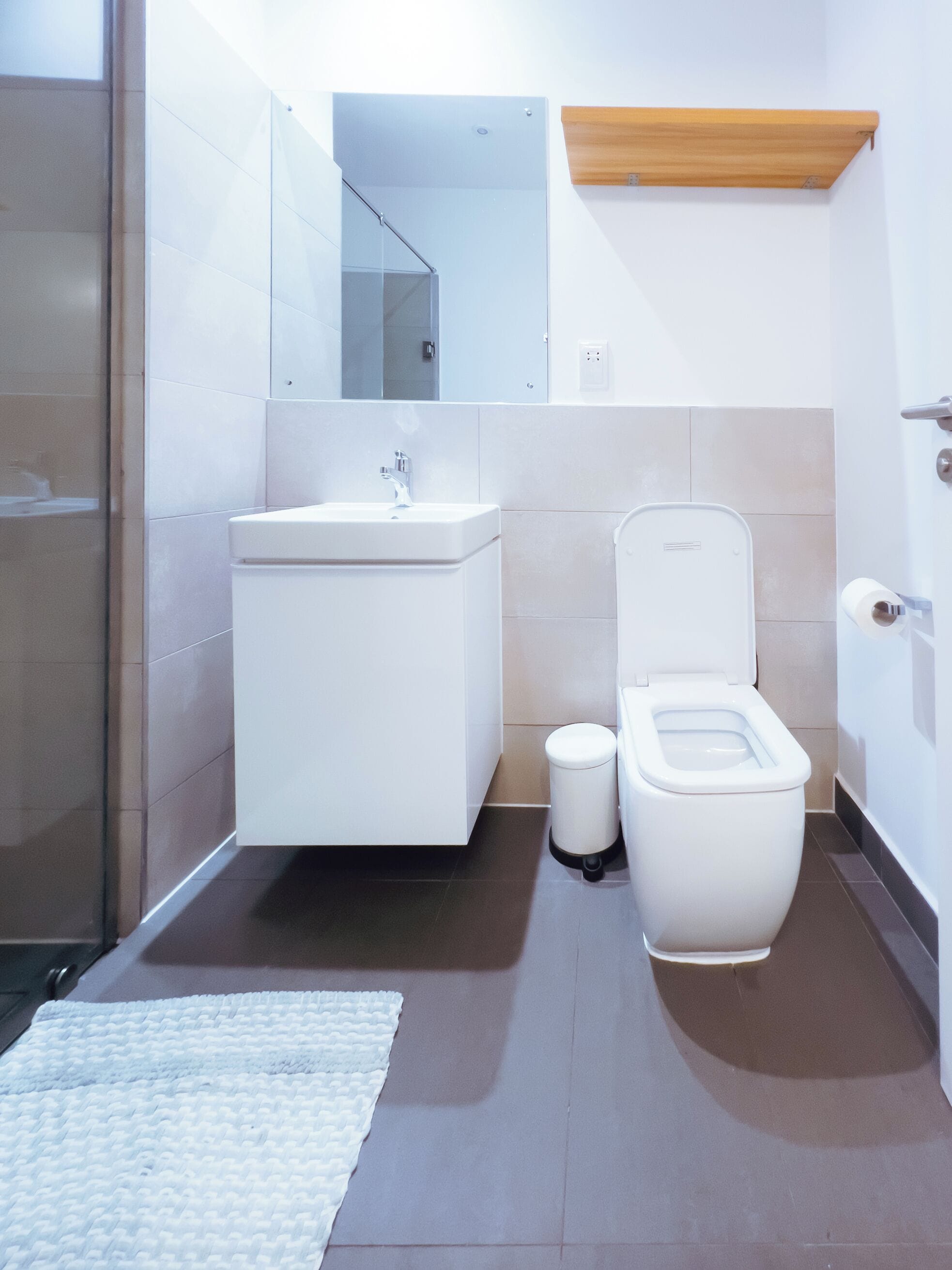 Une salle de bain moderne avec des toilettes, un lavabo et un miroir.