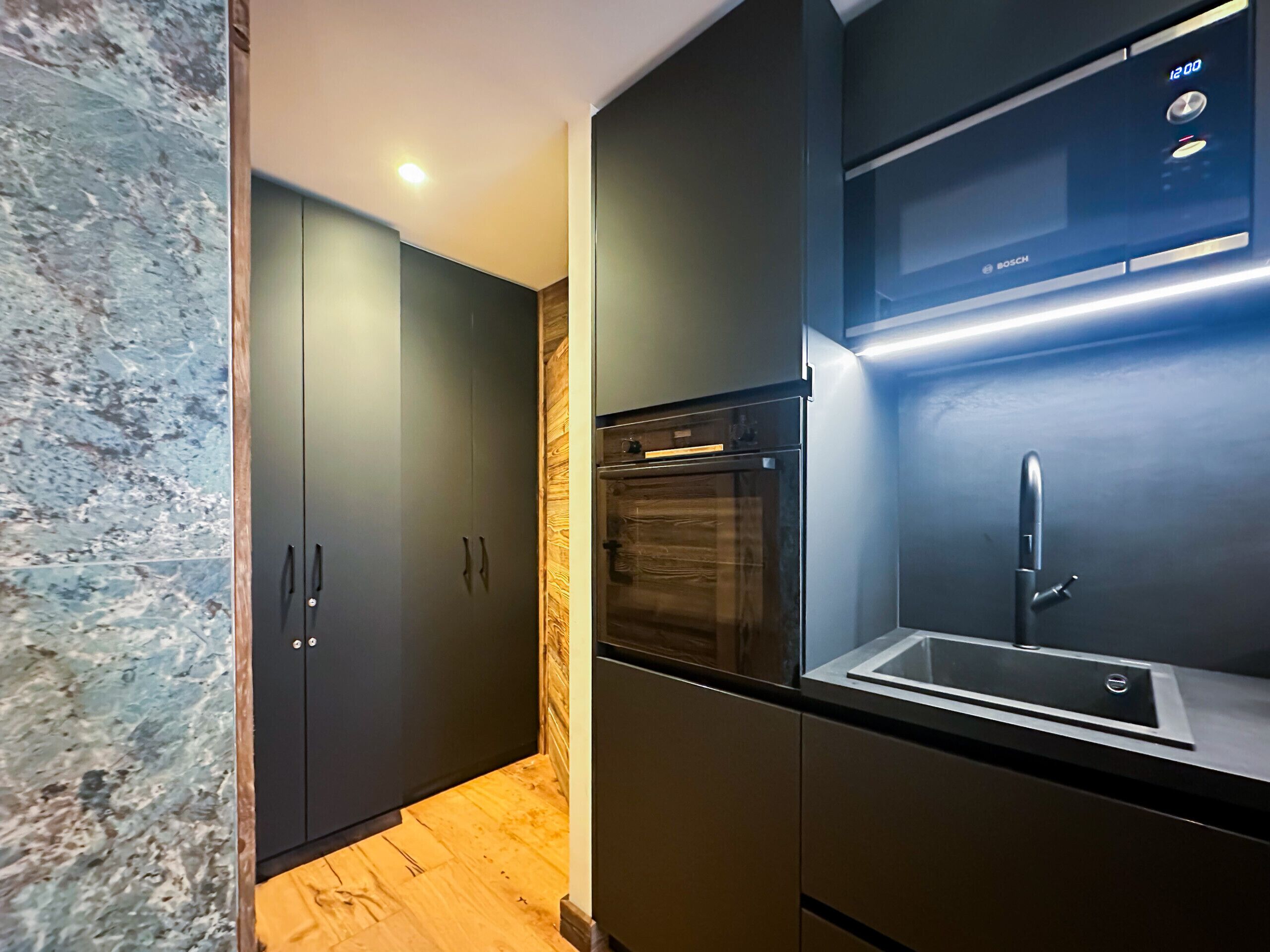 A modern kitchen with a built-in oven, a sink, and a Bosch microwave.