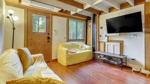 Ein gemütliches Zimmer mit Holzbalkendecke, einem Bett, einer Couch, einem Fernseher und einem Fenster.