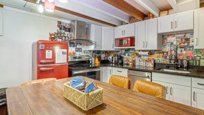 Eine Küche mit weißen Schränken, einem roten Kühlschrank und einem Holztisch mit einer Leckerschnecke.