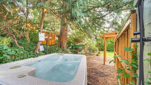 Ein Whirlpool in einer bewaldeten Gegend mit einer Holzpergola und einem Schild.