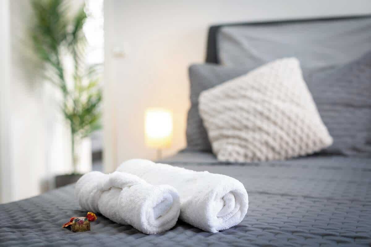 Ein ordentlich gemachtes Bett mit einer grauen Decke, einem weißen Handtuch und einem kleinen dekorativen Gegenstand.