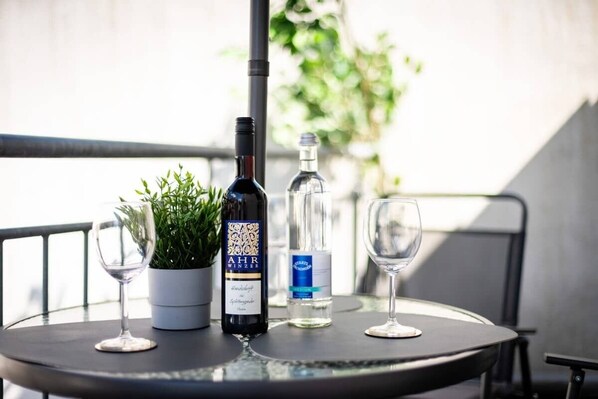 A round table with a bottle of wine, a glass, a potted plant, and a bottle of water. - MOLA Apartments-Klimaanlage, Zentrum,Balkon,Seenah (Herdecke)