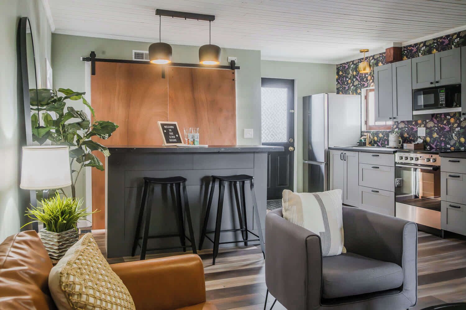 Une cuisine moderne dotée d’un îlot central, de tabourets de bar et d’un coin salon avec un canapé et un fauteuil.