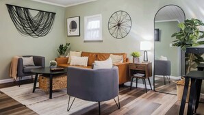 A modern living room with a sofa, armchairs, a coffee table, and a side table with a lamp. - Tiny Home fit for a King: Near Belmont Park! (Dayton)