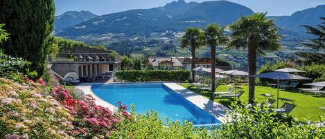 Una piscina circondata da una vegetazione rigogliosa e con vista sulle montagne.