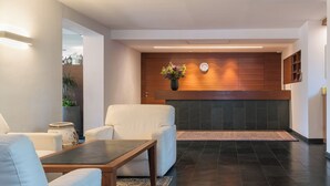 A modern lobby with a fireplace, seating area, and a clock on the wall. - Apartment with large south-facing terrace, incl. garage parking space (Dorf Tirol)