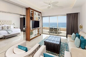 Ein modernes Hotelzimmer mit einem großen Bett, einem Fernseher, einer Couch und Blick auf den Ozean.