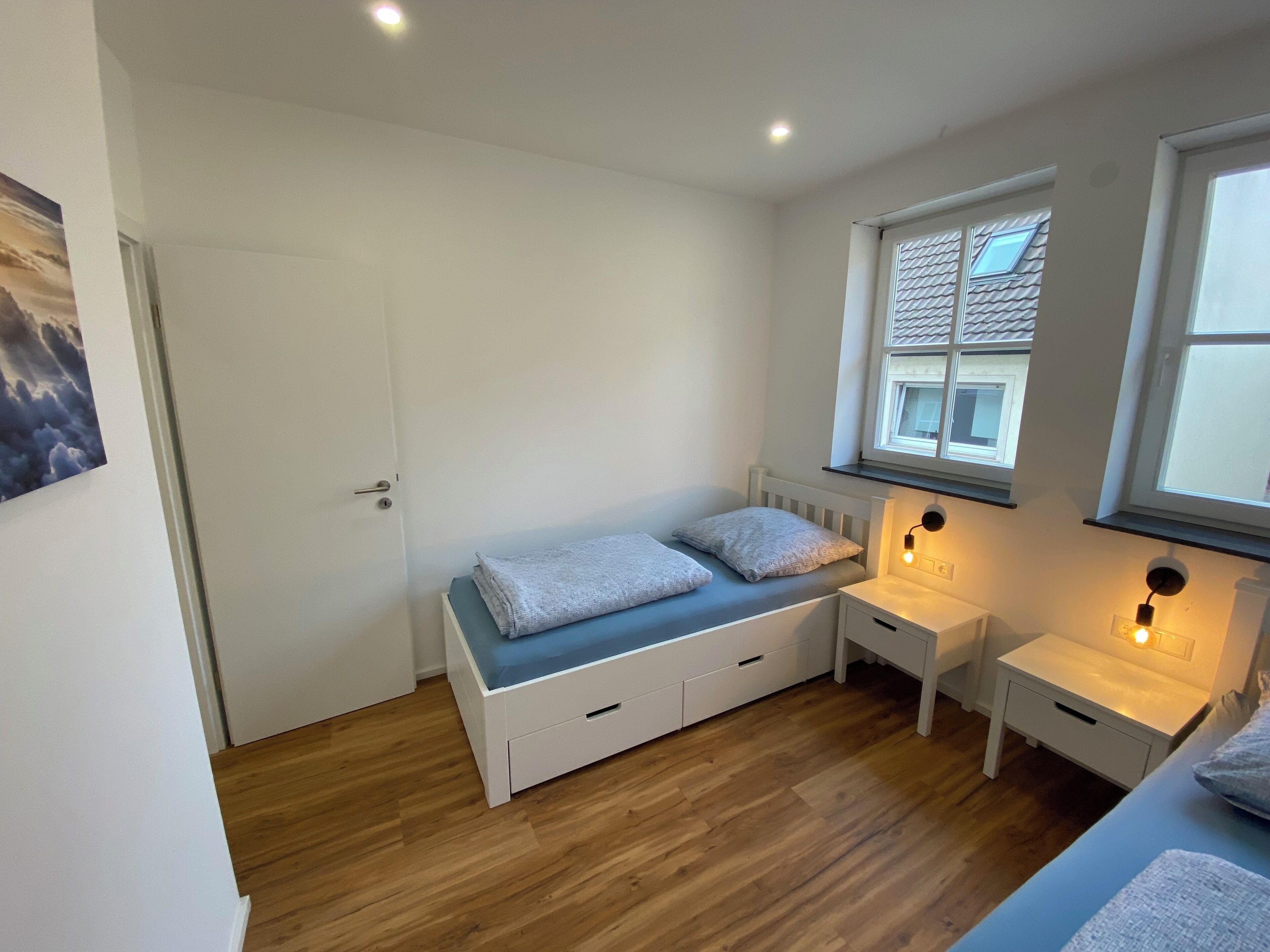 A bedroom with a bed, bedside tables, a window, and a door.