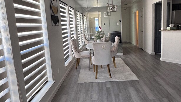 A spacious living room with a large dining table, comfortable seating, and a kitchen area visible through an open doorway. - Modern 2BR,2BA Retreat near AT&T Stadium, Six Flags & Epic Waters, globe  (Arlington)