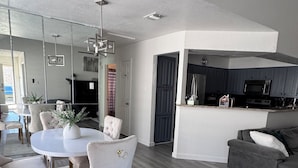 A modern living room with a dining area, grey wooden flooring, and a grey sofa. - Modern 2BR,2BA Retreat near AT&T Stadium, Six Flags & Epic Waters, globe  (Arlington)