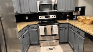 A modern kitchen with grey cabinets, stainless steel appliances, and a granite countertop. - Modern 2BR,2BA Retreat near AT&T Stadium, Six Flags & Epic Waters, globe  (Arlington)