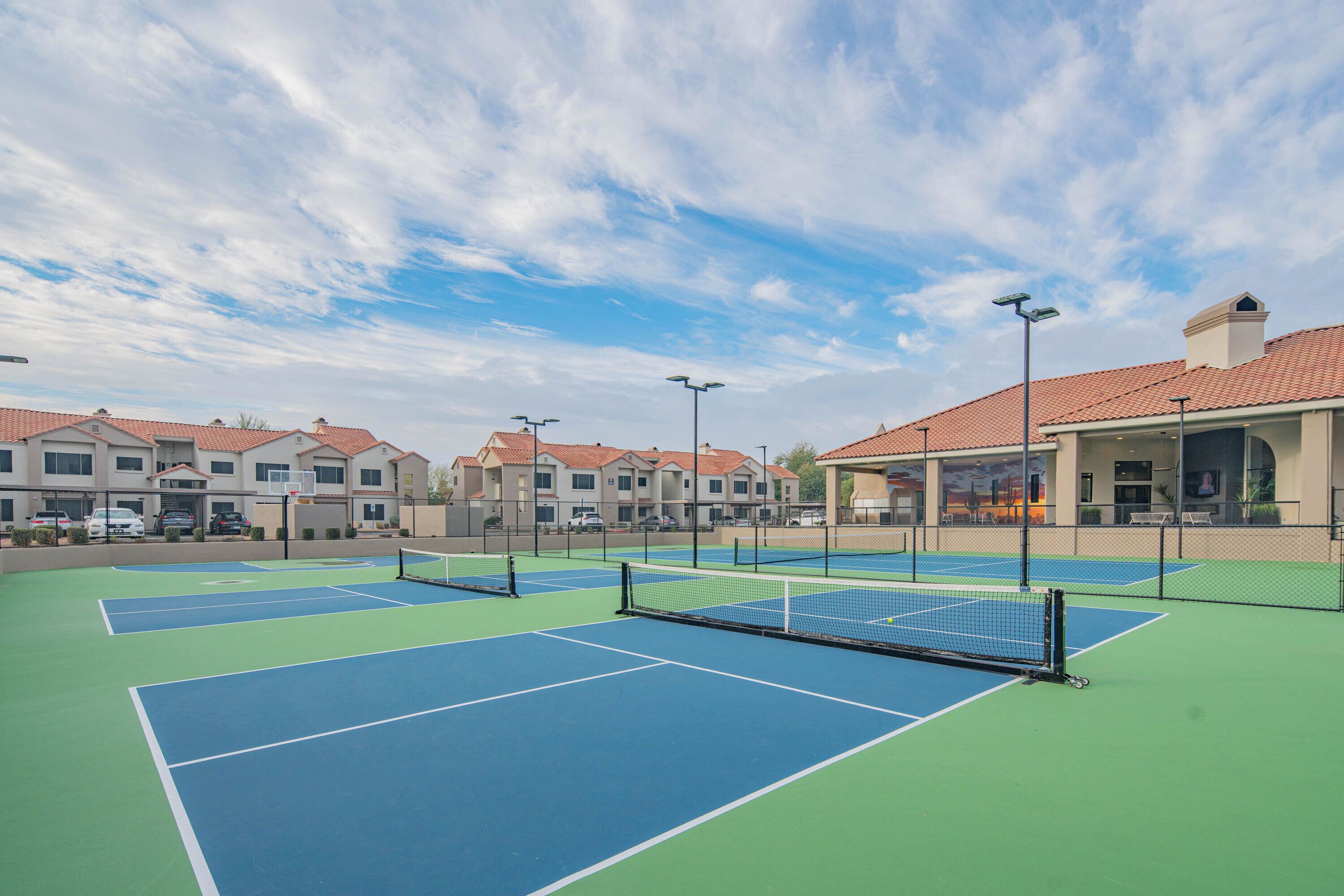 Canchas de tenis múltiples, rodeadas de edificios con techos de tejas rojas.