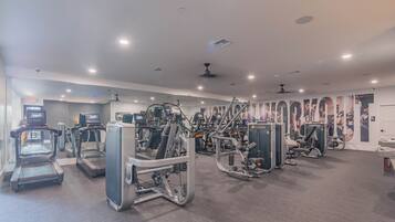Un gimnasio con cintas de correr, elípticas y equipo de pesas.