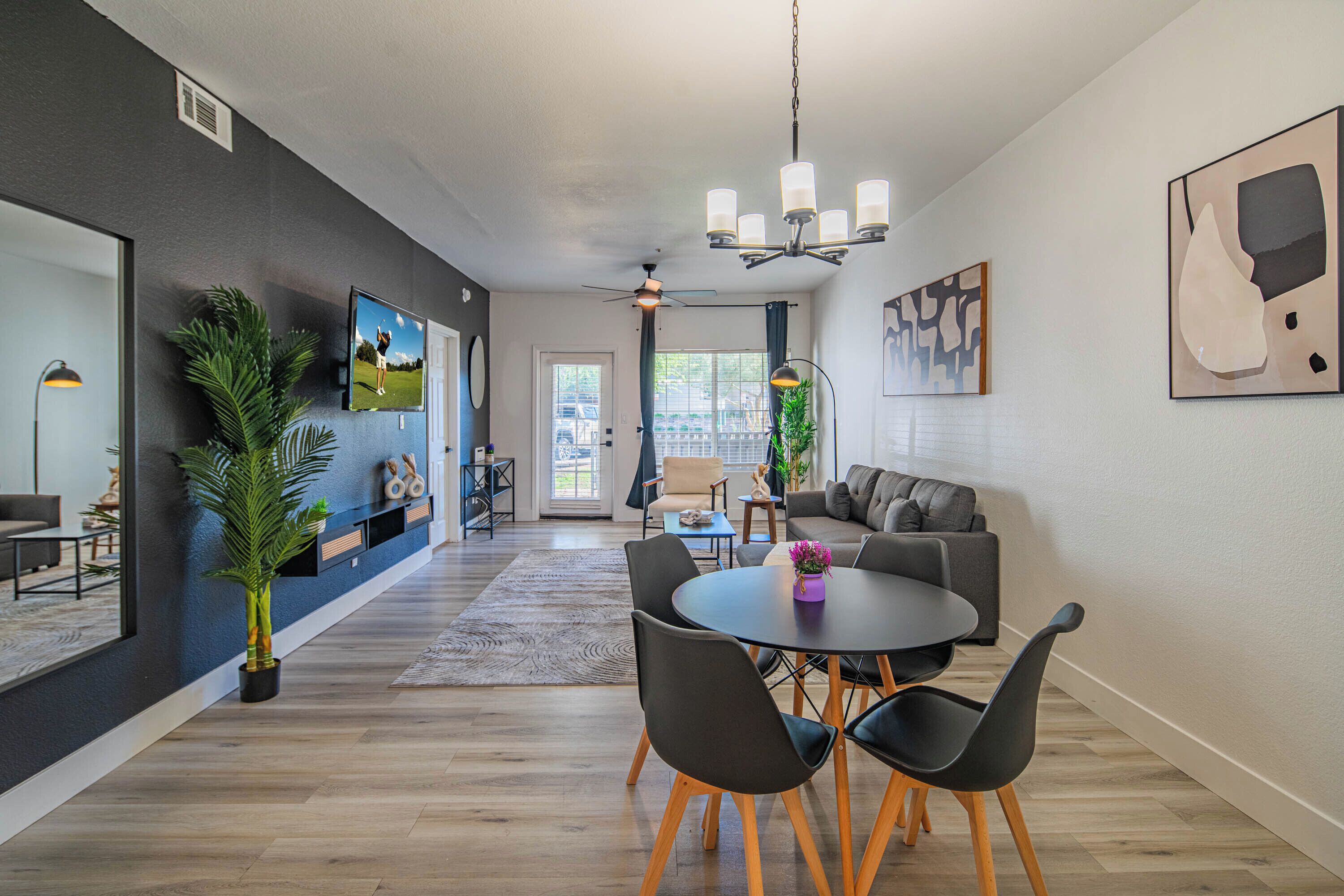 Una sala de estar moderna con comedor, ventilador de techo y un ventanal grande.
