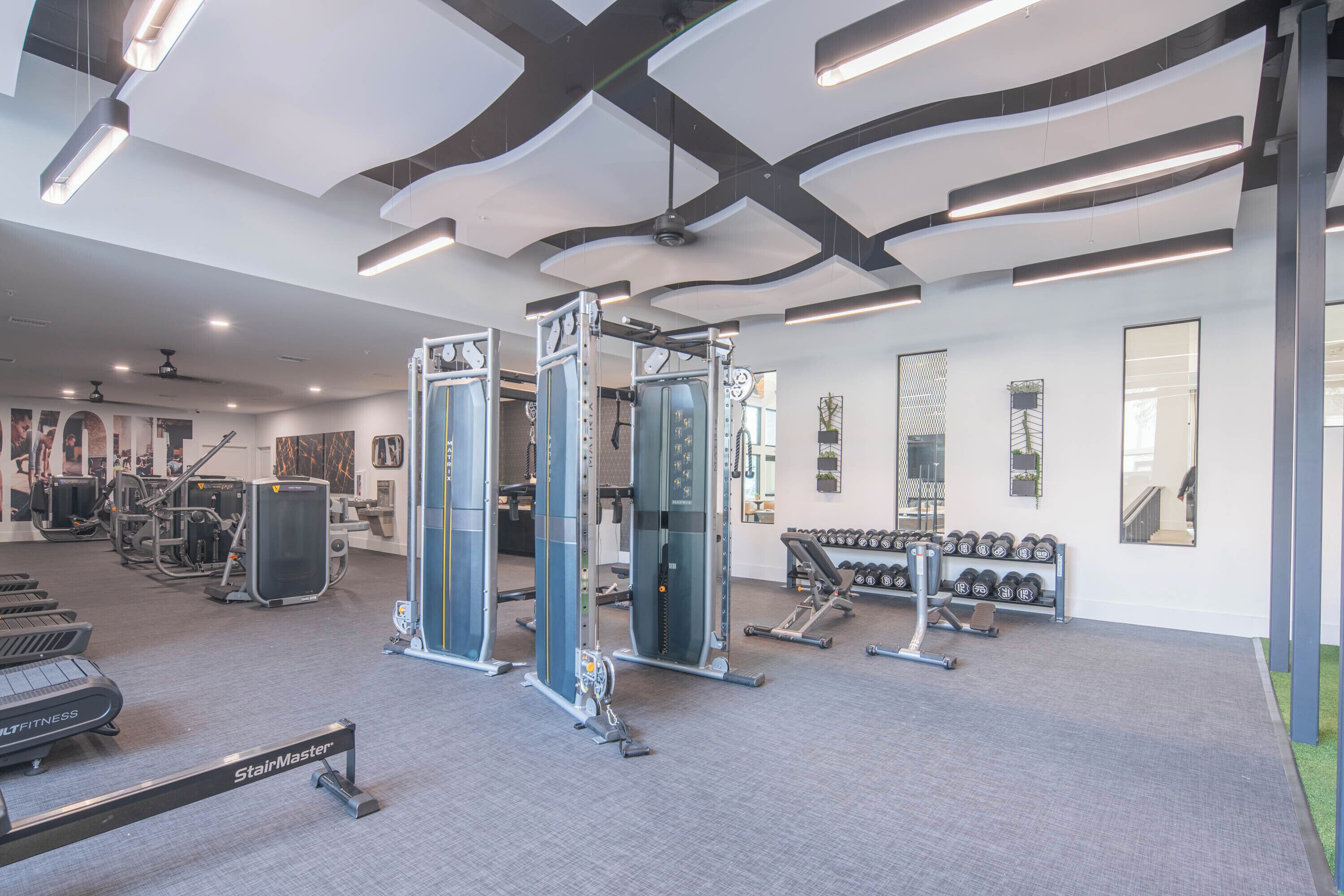 A modern gym with treadmills, weight machines, and dumbbells.