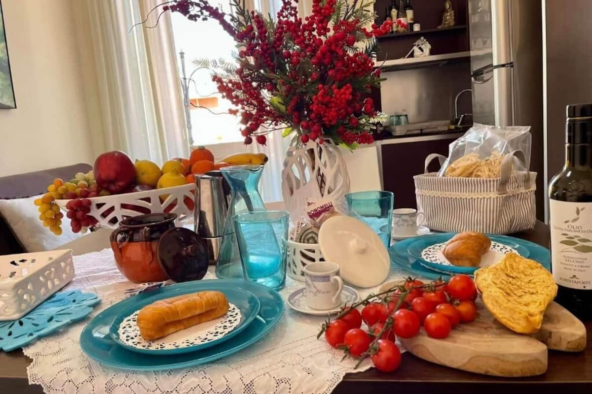 A dining table set with plates, glasses, a vase with red berries, and various food items.