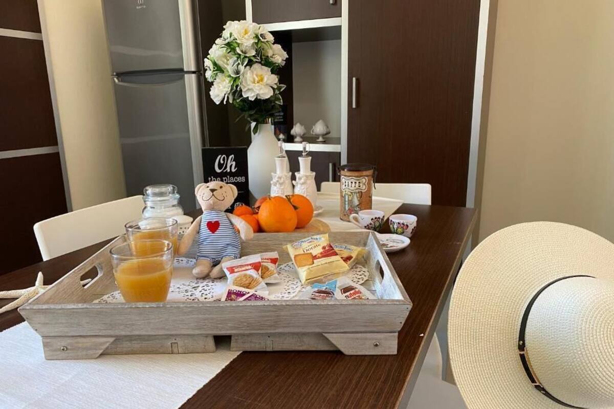 A breakfast tray with orange juice, cereal, and pastries on a wooden table.