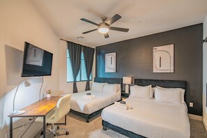 Habitación de hotel con dos camas, un escritorio, una silla, un televisor y un ventilador de techo.