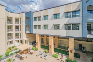 Un hotel de varios pisos con áreas de estar al aire libre, piscina y un patio cubierto.