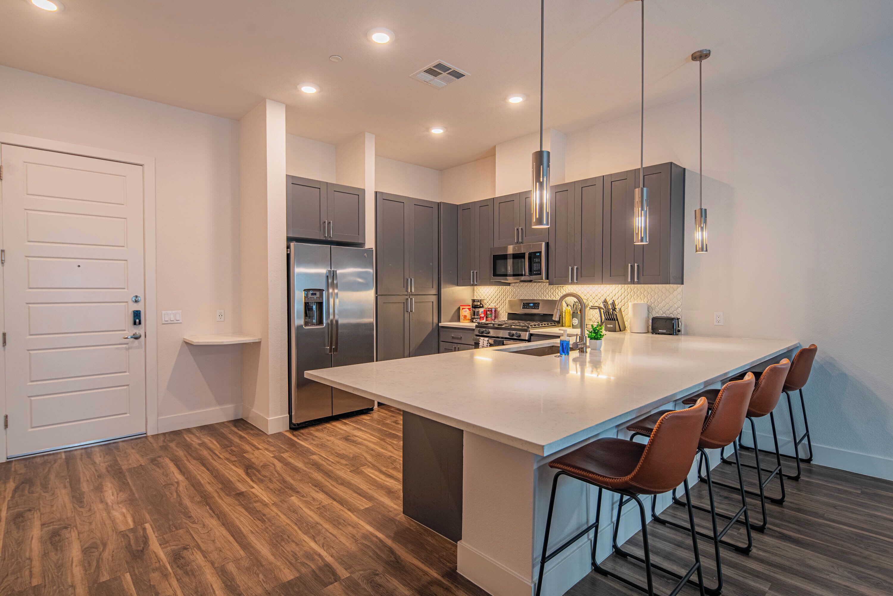 A modern kitchen with a large island, stainless steel appliances, and bar stools.