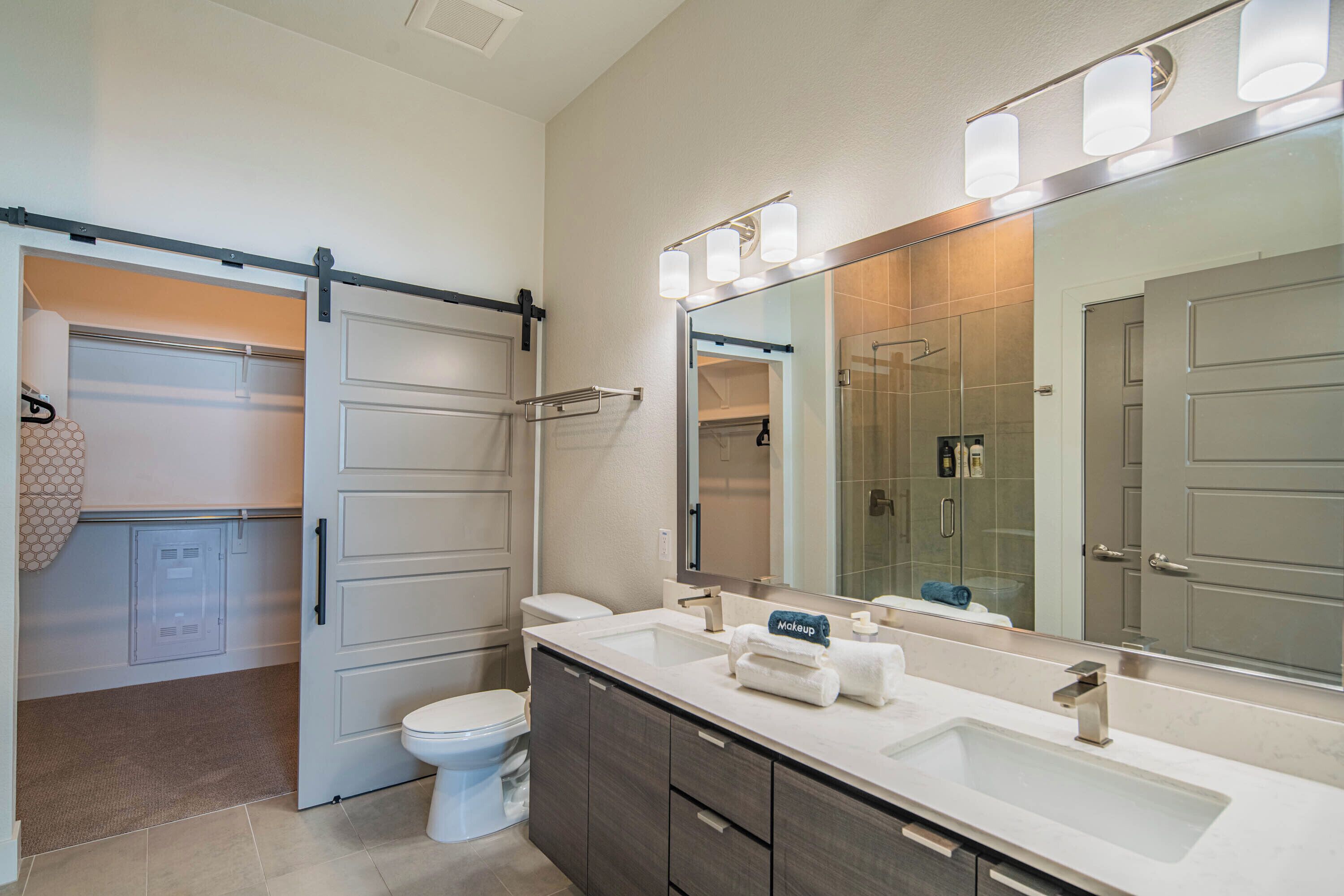 A modern bathroom with a large mirror, a sink, and a toilet.