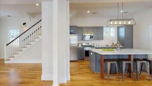 Een moderne keuken met een centraal eiland, roestvrijstalen apparatuur en een trap naar een ander niveau.