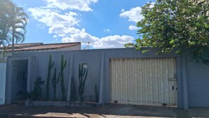 Un edificio residenziale con un'anta di garage in metallo ondulato, un muro di cemento decorato con un murale di cactus e un cielo azzurro limpido.