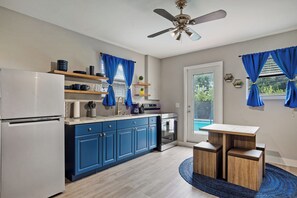 Eine moderne Küche mit blauen Schränken, einem Edelstahlkühlschrank und einem Deckenventilator.