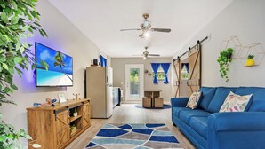 Una sala de estar moderna con un sofá azul, un aparador de madera y un televisor grande.