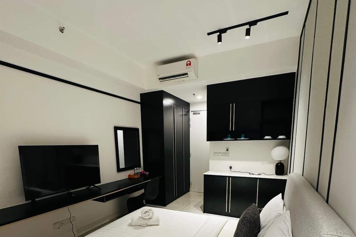A modern hotel room with a large bed, a flat-screen TV, a desk, and a wardrobe.