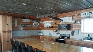 Een ruime keuken met een groot kookeiland, houten kastjes en moderne apparatuur.