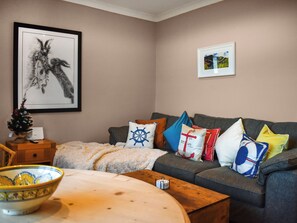 A living room with a grey sofa, a small wooden table, a bowl, and a framed picture on the wall. - Marina Views, your peaceful coastal escape in the heart of Amble. (Morpeth)