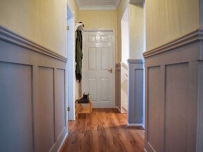 Un pasillo con suelo de madera y puertas blancas que conduce a una habitación.