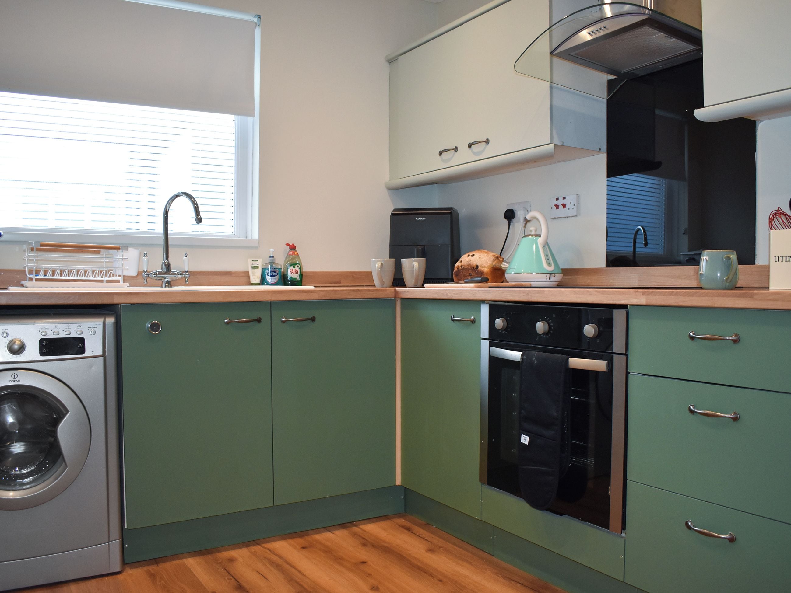 A compact kitchen with a washing machine, a toaster, and a kettle.