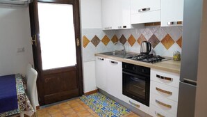 Una cocina compacta con armarios blancos, una estufa a gas, un horno y un lavamanos.
