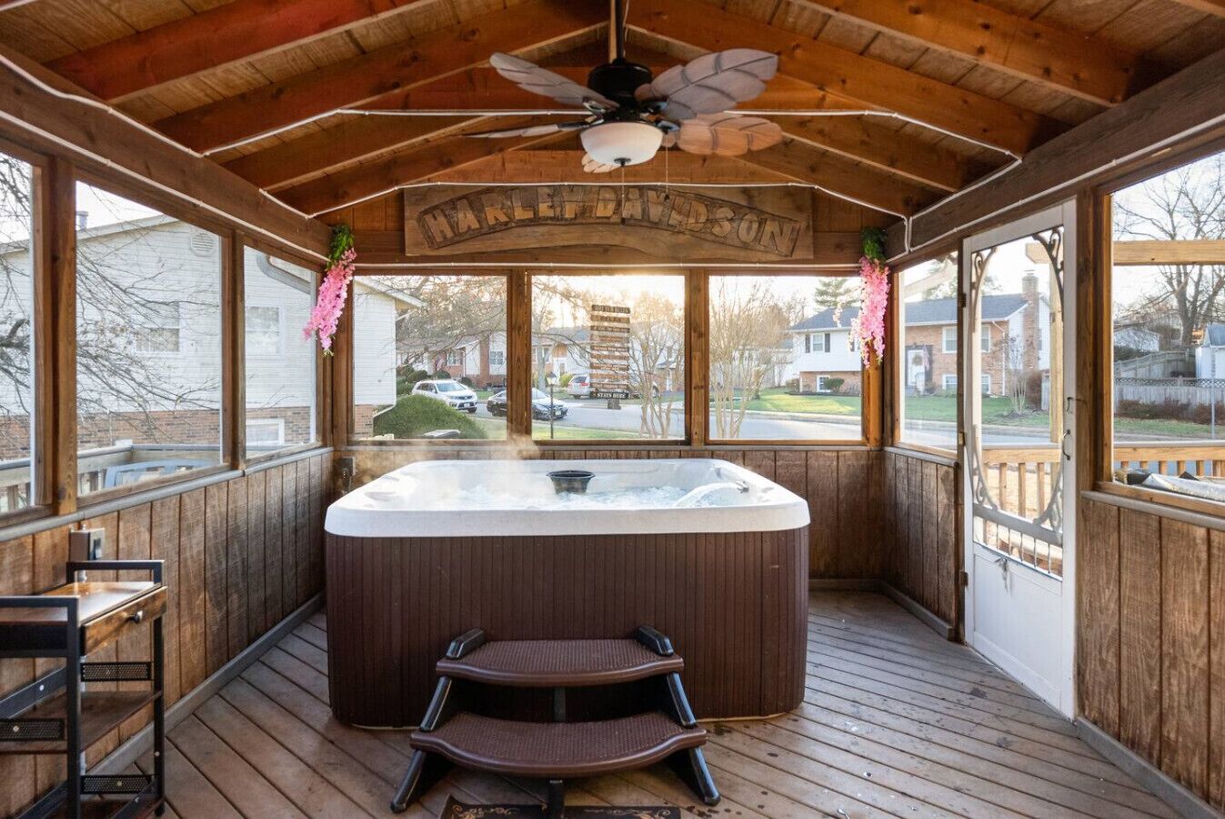 Een houten terras met een jacuzzi, een plafondventilator en een bord waarop 'HARLEY-DAVIDSON' staat.