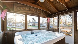 Un espace de détente en bois comprenant un jacuzzi, de grandes fenêtres et une enseigne indiquant « HARLEY-DAVIDSON ».