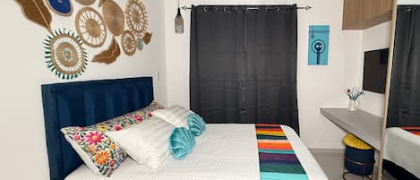 Un dormitorio con cama, escritorio, silla, espejo y decoración mural.