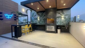 An outdoor kitchen area with a bar, seating, and a neon sign. - Dept. Unique the best of Equipe (Santa Cruz de la Sierra)