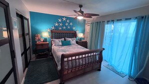 Ein Schlafzimmer mit einem Bett, Deckenventilator, Wanddekoration mit Sternen und einem Fenster mit Vorhängen.