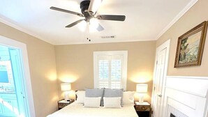 Une chambre à coucher avec un lit, un ventilateur de plafond, une cheminée et une vue sur l’extérieur.