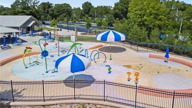 Un terrain de jeux avec des structures colorées et des parasols bleus et blancs.