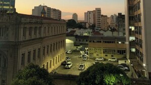 A cityscape at dusk with a parking lot in the foreground, surrounded by buildings of varying architectural styles. - Sua Casa no Rio-Lapa-Lindo Studio (Rio de Janeiro)