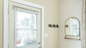 Une porte avec une fenêtre, un porte-manteau, un miroir et un banc en bois.