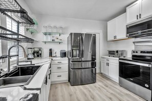 Una cucina moderna con elettrodomestici in acciaio inossidabile, mobili bianchi e pavimento in legno.