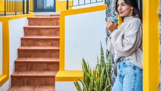 A staircase with yellow railings and a person holding a blue object. - Villa Piedade by Homie (Ponta do Sol)
